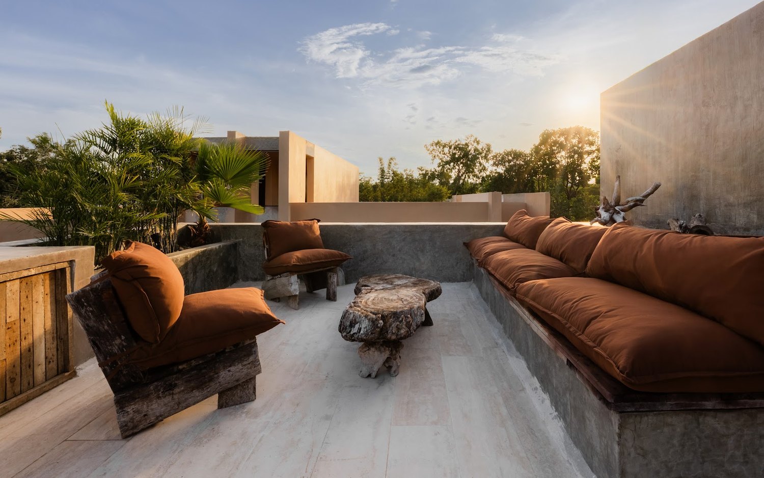 The rooftop lounge at golden hour &mdash; sunset, a cigar corner, and the social heart of the house.